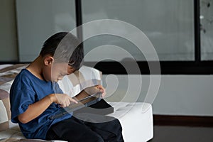 Boy play smart phone tablet in concentration alone in room in family care and ADHD concept