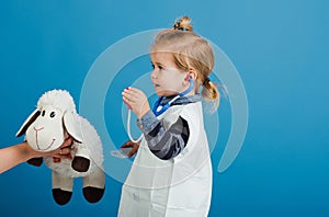 Boy play veterinarian with toy sheep in mothers hand