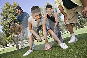 Boy Playing American Football With Group Of Men