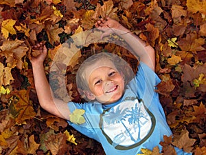 Boy playing in autumn leaves