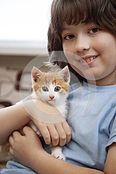 Boy playing with baby cat. Child and kitten at home