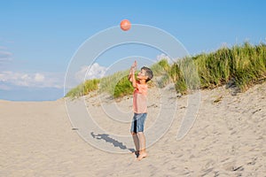 Boy playing with the ball on the beach. Family summer vacation by the sea