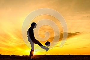 Boy playing with ball in nature, silhouette of playing child
