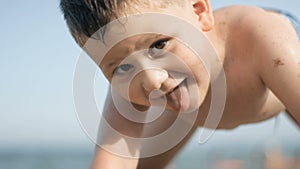 A boy is playing on the beach and showing a tongue
