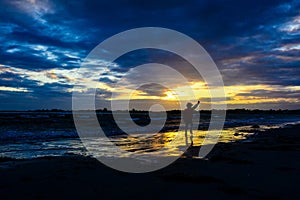 Boy playing on the beach at sunset