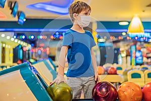 Boy playing bowling with medical masks during COVID-19 coronavirus in bowling club