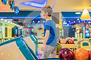 Boy playing bowling with medical masks during COVID-19 coronavirus in bowling club