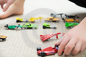 Boy playing with car collection on carpet.Child hand play. Transportation, airplane, plane and helicopter toys for children