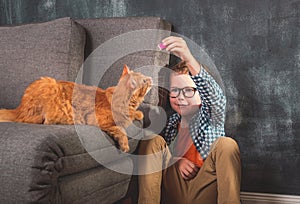 boy playing with a cat. Kid with ginger pet cat.