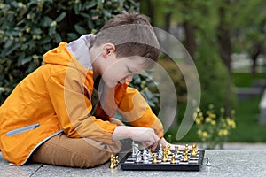 Boy playing chess outdoor. Learning strategic game. Education