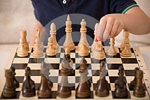 Boy playing chess in the room. Little clever child thinking while playing chess at home. Education concept