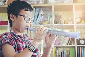 Boy playing the clarinet, trumpet at home, blowing a sweet flute