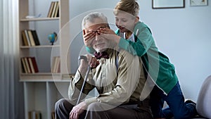 Boy playing and closing grandfather eyes, having fun together on weekends
