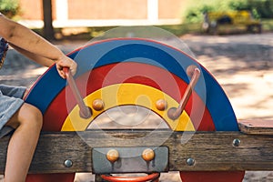 Boy is playing on a colorful seesaw in the playground