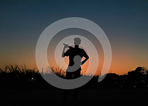 Boy playing cricket in India in the evening.