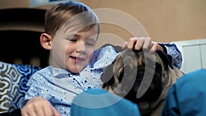 Boy playing with dog in the house on the couch