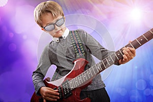 Boy playing electric guitar in talent show on stage