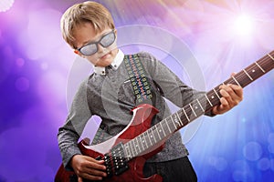 Boy playing electric guitar in talent show on stage photo