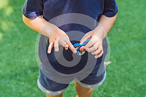 Boy playing with fidget spinner. Child spinning spinner on the playground. Blurred background