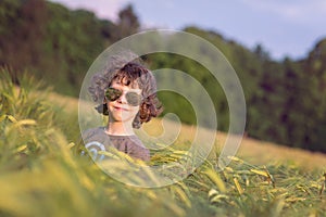 Boy playing on the filed in sunset, sunglasses