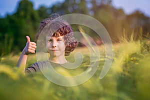 Boy playing on the filed in sunset, Thumbs up!