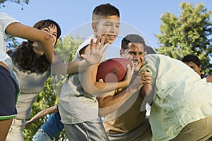 Boy (13-15) playing football with family. photo