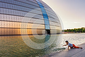 Boy playing in front of the National Centre of Performing Arts in Beijing, China