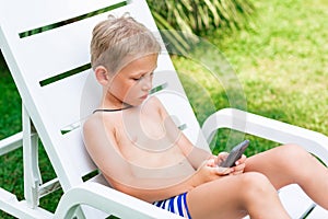 Boy playing games on the telephone. Gadget dependency disorder problem for kids during holiday vacation at the seaside