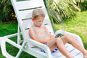 Boy playing games on the telephone. Gadget dependency disorder problem for kids during holiday vacation at the seaside