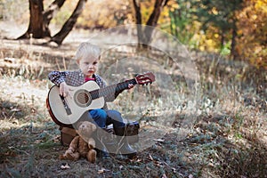 Boy playing guitar in autumn forest