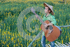 Boy playing guitar in Beautiful Sunhemp flower