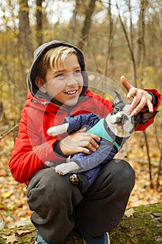 A boy playing with his dog in the woods.