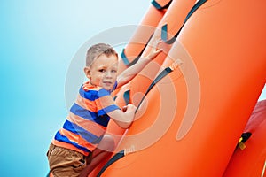 Boy playing on an inflatable playground on the beach on a summer