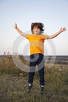 Boy playing jumping on summer sunset meadow