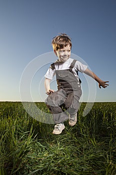 Boy playing jumping on summer sunset meadow