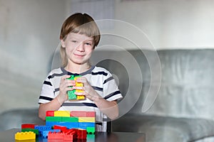 Boy playing with lots of colorful plastic blocks indoor