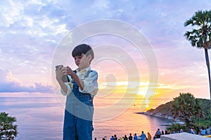 A boy playing on mobile at Promthep cape viewpoint