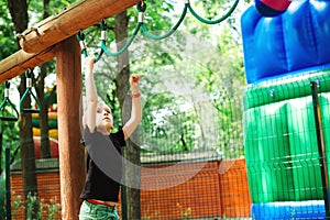 Boy playing on monkey bars. Summer vacation, camp and leisure. Healthy childhood. Strong litlle boy training outside