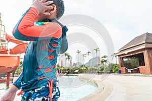 Boy playing next to a water slide in aqua water park