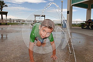 Boy playing in an outdoor water splash pad