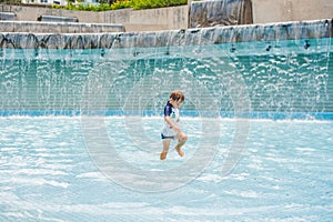 Boy playing in the paddling pool in the summertime