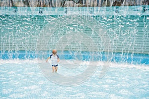 Boy playing in the paddling pool in the summertime