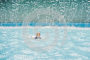 Boy playing in the paddling pool in the summertime