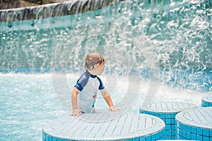 Boy playing in the paddling pool in the summertime