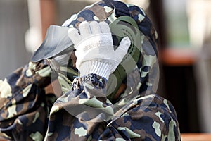 Boy is playing paintball on the field. two teams of paintball players in camouflage form with masks, helmets, guns on the field