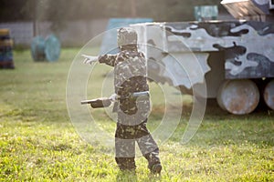 Boy is playing paintball on the field. two teams of paintball players in camouflage form with masks, helmets, guns on the field