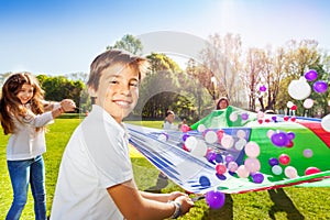 Boy playing parachute with friends in summer park