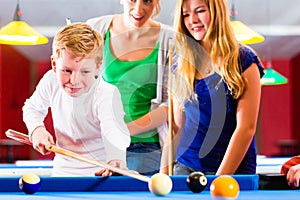 Boy playing pool billiard with family