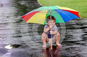 Boy playing in the rain with umbrella