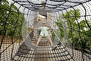 Boy playing in rocket slide ropes at children`s playground in public park